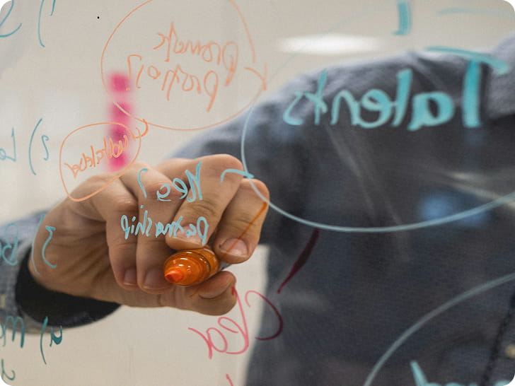 Main qui structure des idées sur une vitre pendant un atelier collaboratif